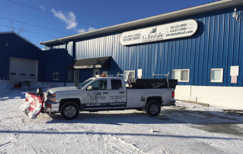 G. Fedale roofing & siding building in winter with a truck that has a snowplow on front.