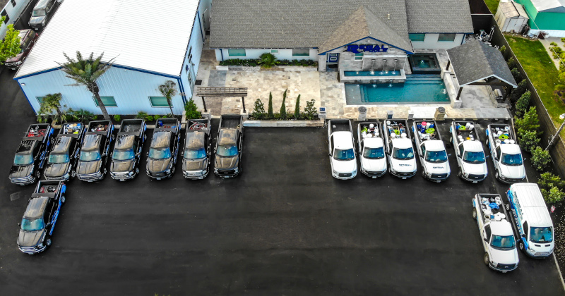Regal Pools office building aerial view with work vehicles parked out back.