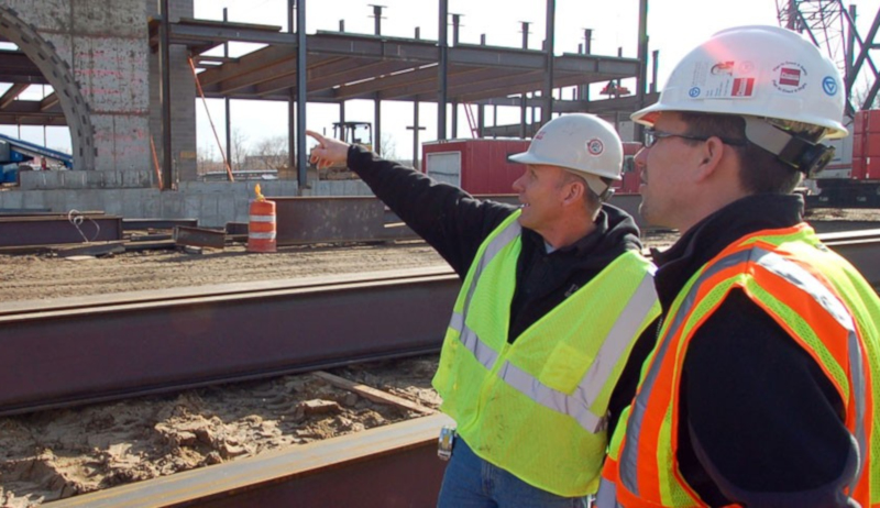 Pioneer Construction employees talking and pointing at a construction site.