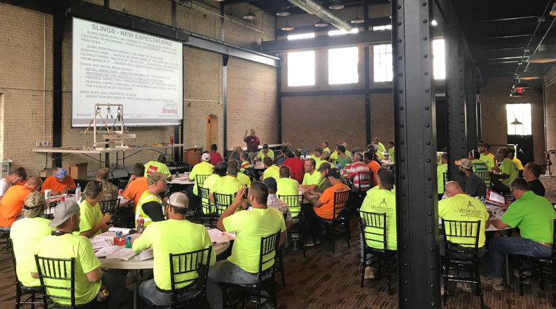 Pioneer Construction employee training with people sitting at tables with a screen showing information.